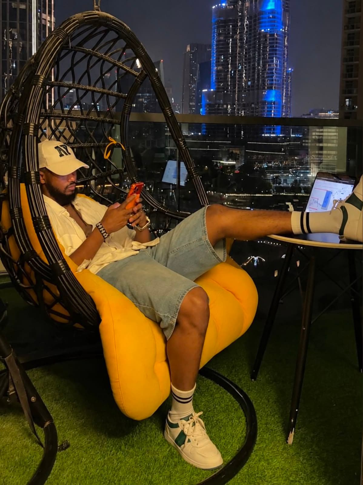Ahmed working from a balcony above the Dubai skyline at night
